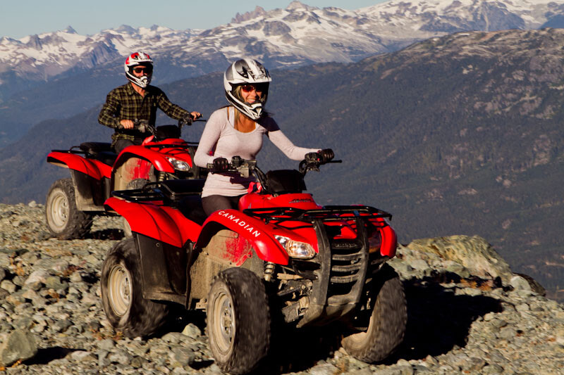 Man and woman riding ATV's in the mountains of Whistler